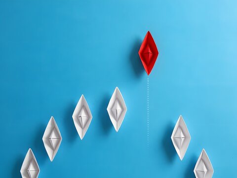 Red paper boat leading white boats for business leadership and innovation concept, blue background