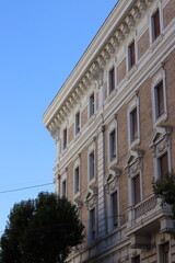 Obraz premium A grand neoclassical building facade with ornate white stucco moldings, arched windows, and decorative cornices against a clear blue sky.