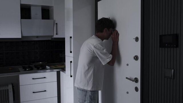 Anxiety disorder and psychological stress concept with nervous man checking door peephole, fear, tension and unsafe feeling at home