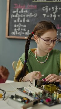 Vertical shot of multiethnic children assembling computer motherboard in science class. Clip is perfect for marketing elementary school STEM programs and technology courses