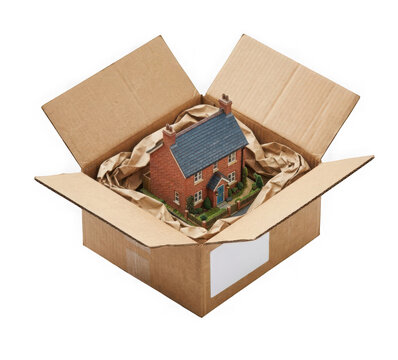 A miniature model of a brick house inside a cardboard shipping box with packing paper isolated on transparent background