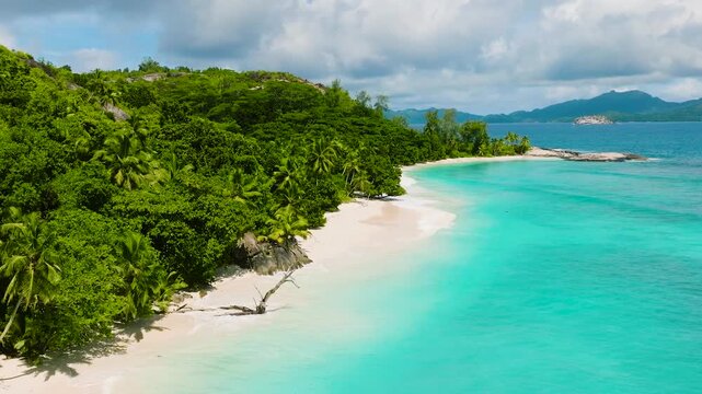 Green hills extending to the turquoise ocean, with lush vegetation and blue skies. Therese. Seychelles, Mahe.