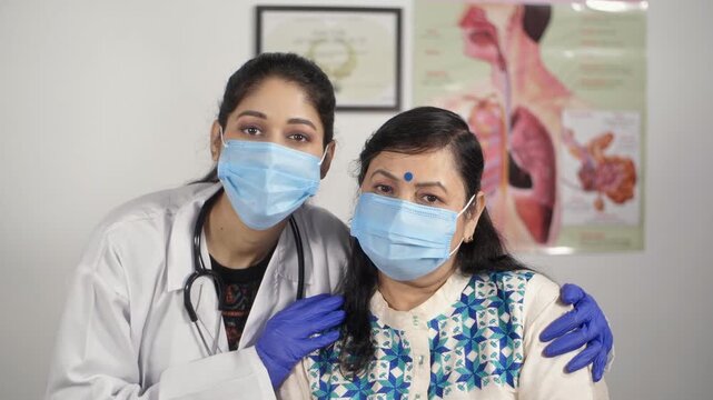 A young doctor and her patient wearing a medical mask posing together. A medical practitioner showing empathy to an elderly woman patient during Coronavirus outbreak - old people healthcare