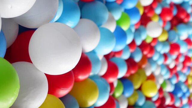 Brightly colored plastic balls fill frame in dynamic motion, abstract background texture