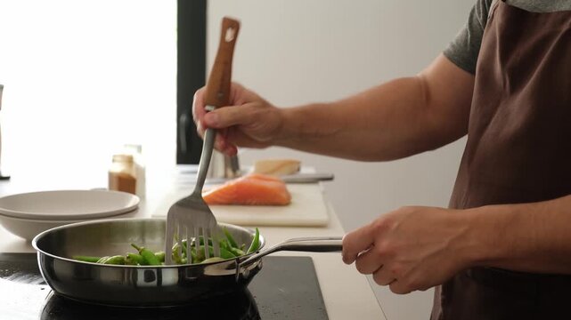 Professional chef sauteing green peppers and seasoning them before covering the pan with a lid