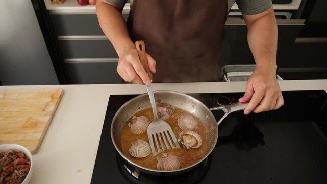 Professional chef preparing a delicious seafood dish with scallops in a modern kitchen