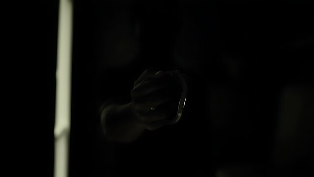 A blurred figure in shadows with illuminated handcuffs in the foreground.