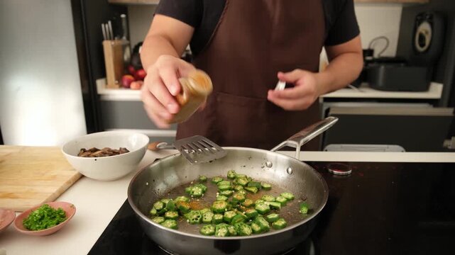 Professional chef preparing a healthy vegan meal by stir frying fresh okra with spices