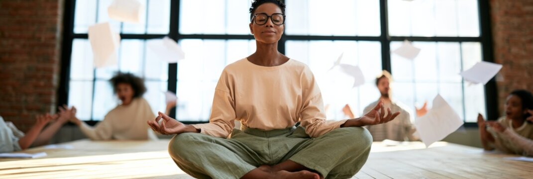 Woman meditating seated in lotus pose in office studio amid flying papers for workplace mindfulness and stress relief background