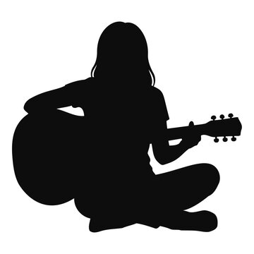 Silhouette of a young girl sitting cross-legged and playing an acoustic guitar