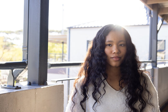 Female child standing on balcony wearing light knit sweater beside metal railing and concrete ledge