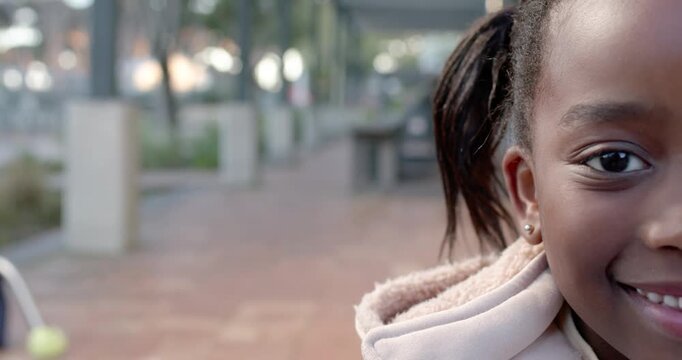 Child African descent entering arcade in right frame smiling wearing padded coat studs, copy space