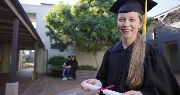 Female grads gowned in quad grad holding rolled diploma checking laughing as camera nears cheering