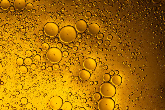 Golden yellow oil bubbles floating on water surface