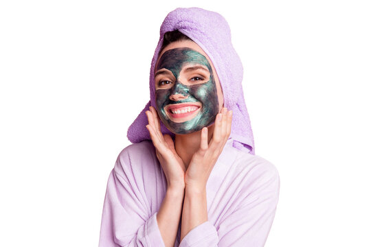 Close-up portrait of attractive cheery girl wearing towel turban on head applying natural clay mask on face isolated over pink pastel color background