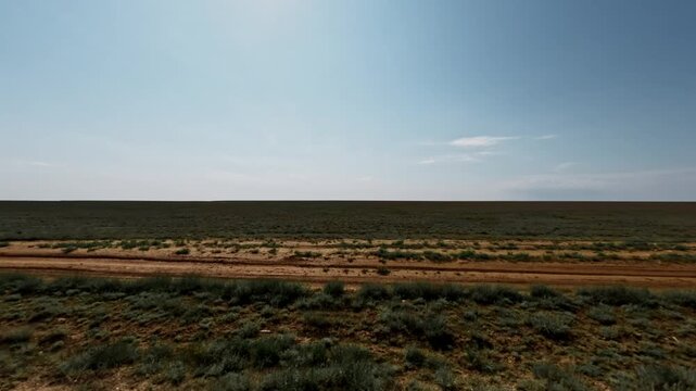 SUV driving off-road across open terrain under clear blue sky