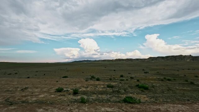 SUV driving off-road through expansive landscape with clouds in the distance