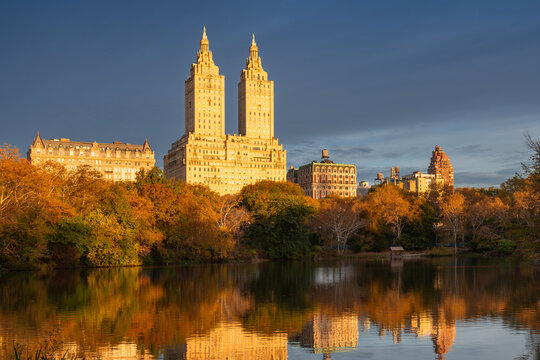 Central Park autumn foliage reflected in The Lake with the Upper West Side skyline in warm morning light, Manhattan, New York City, USA