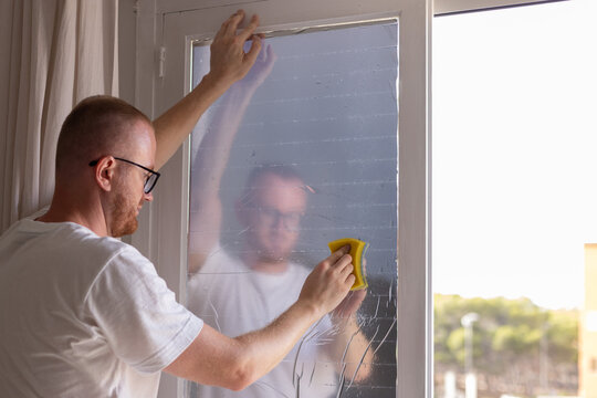 Man tinting windows at home with sun protection film.