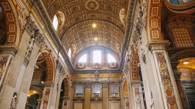 Low angle view of ornate vaulted ceiling inside Saint Peters Basilica in Vatican City.