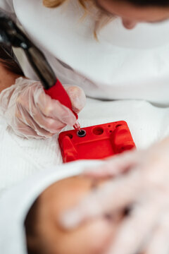 Close-up view of a cosmetic specialist wearing gloves and preparing equipment for a precise eyebrow tattooing procedure in a sterile clinic setting.