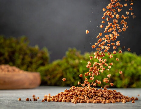 Whole grain buckwheat groats cascading onto a neutral stone surface with a dynamic sense of motion.