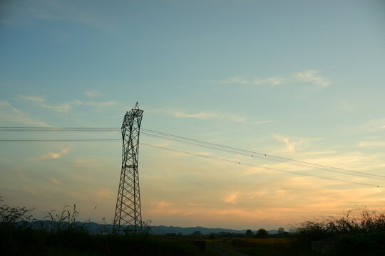 High voltage electricity pylon and power lines in silhouette at sunset with copy space