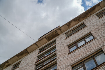 Low angle view of an old white brick apartment building under dramatic cloudy sky © Kasya
