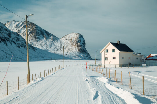 Snow-covered road leading to traditional house, Lofoten Islands, Norway