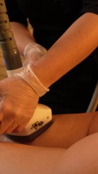 Vacuum roller massage. Anti-cellulite stage. Dim atmospheric warm light. Masseuse massages a woman's leg and thighs with a device. self-care, care, weight loss. slow motion