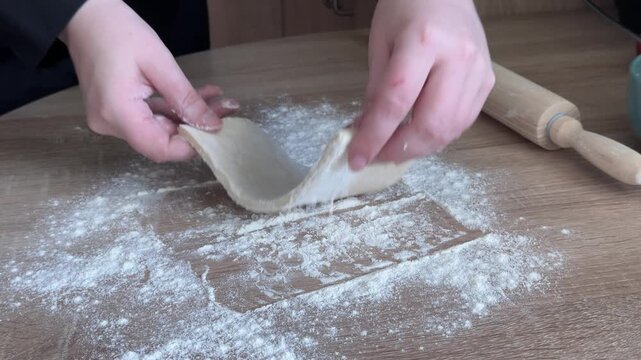Rolling out puff pastry with wooden rolling pin for homemade apple strudel preparation