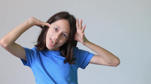 Playful preteen girl making funny face with tongue out, expressive childhood emotions and silly gesture on camera