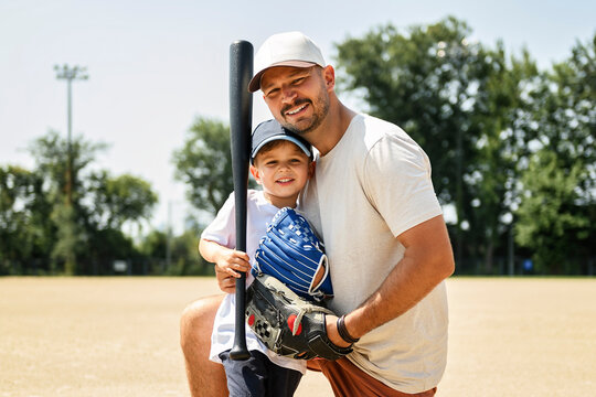Father and son playing baseball in summer day at public park
