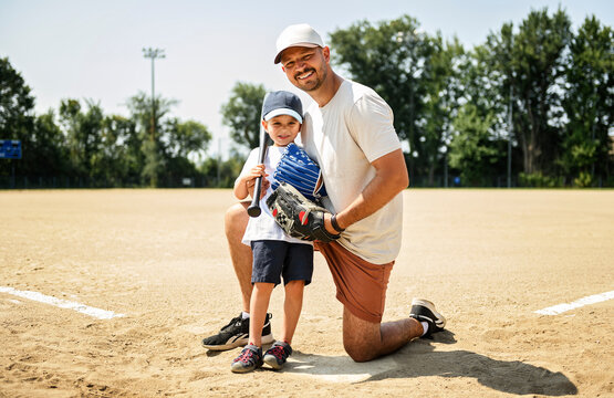 Father and son playing baseball in summer day at public park