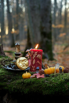 burning red magic candle in candlestick, moon amulet, crystals, decorative pumpkins in autumn forest. mystery fairy tale scene. Witchcraft, esoteric spiritual ceremony. magic ritual. witch aesthetic