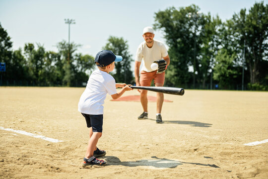 Father and son playing baseball in summer day at public park