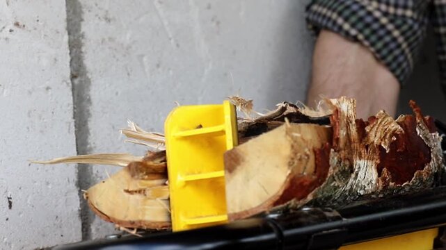 Manual log splitter helps divide dry birch wood into small pieces for a fire during a bright afternoon session inside a workshop space to prepare fuel for winter heating