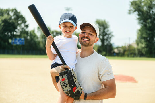 Father and son playing baseball in summer day at public park
