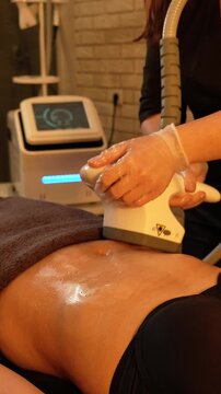 Vacuum roller massage. Anti-cellulite stage. Dim atmospheric warm light. Masseuse massages a woman's stomach with a device. self-care, care, weight loss. slow motion