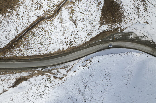 Aerial top view of a car driving  in frozen road