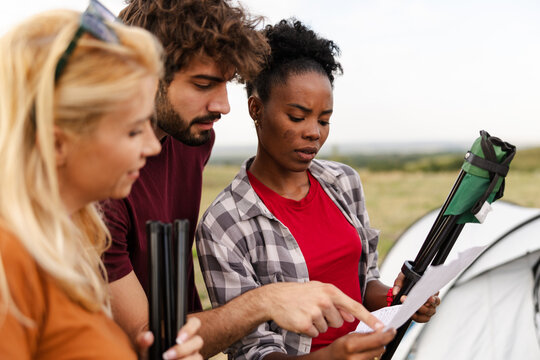Group Checks Camping Instructions in a Field While Preparing to Set up Tent