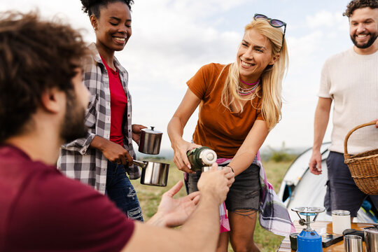 Friends Preparing Coffee and Enjoying Time Together While Camping in a Grassy Field During the Day