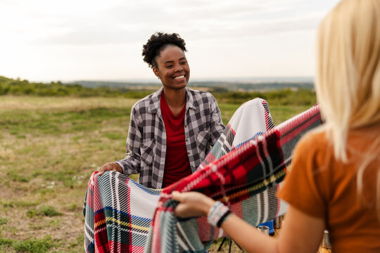Friends Sharing a Blanket in an Outdoor Setting During a Camping Trip
