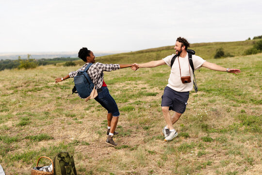 Couple Enjoying Outdoor Activity in Nature Holding Hands and Dancing in a Grassy Field