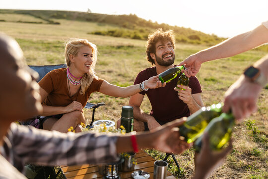 Group of Friends Sharing Drinks While Camping in an Open Field During the Day