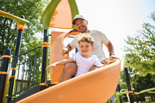 Happy boy kid on slider playground on summer season with his father