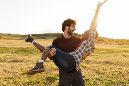 Couple Enjoying Outdoor Fun in a Field During Sunset Near Hills