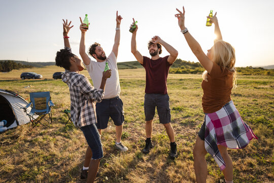 Group of Friends Celebrating Outdoors With Drinks in a Grassy Field