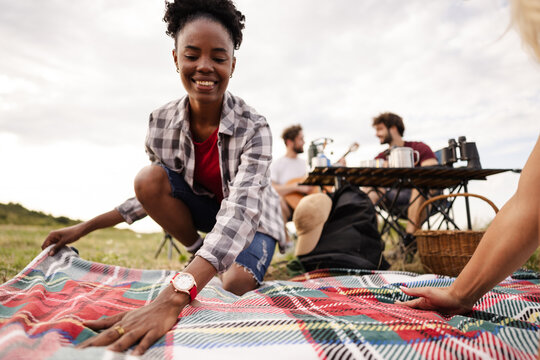 Enjoying a Picnic on a Blanket During a Sunny Day in the Outdoors With Friends and Camping Gear