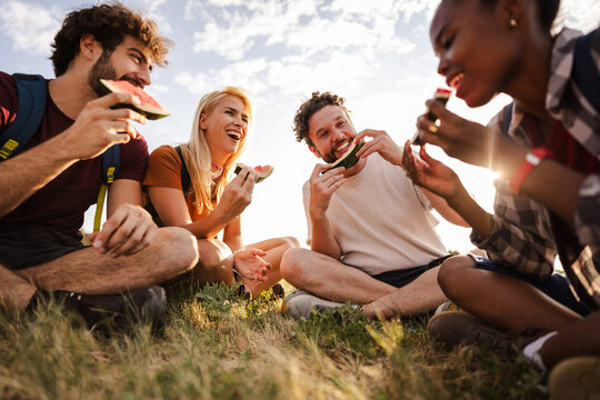 Friends Enjoying Watermelon at Sunset While Camping Outdoors